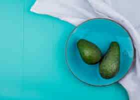 Gratis foto bovenaanzicht van groene avocado's op een plaat op blauwe ondergrond