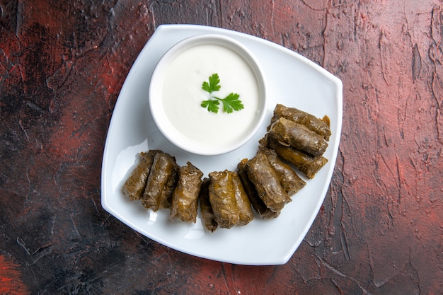 Bovenaanzicht van groene blad dolma met yoghurt op het donkere oppervlak