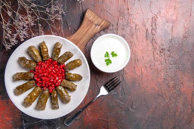 Gratis foto bovenaanzicht van groene blad dolma met yoghurt op het donkere oppervlak