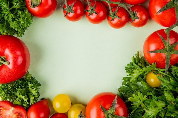 Bovenaanzicht van groenten als koriander en tomaat op wit met een kopie ruimte