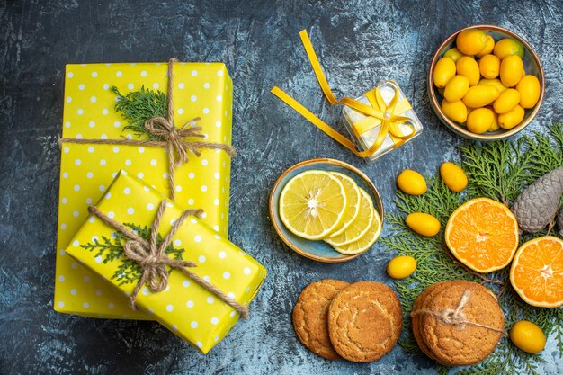 Bovenaanzicht van halve en hele verse citrusvruchten en gele geschenkdoos conifer kegels heerlijke koekjes op donkere achtergrond