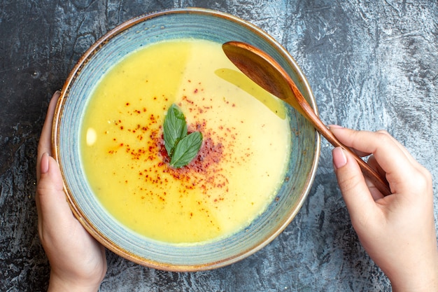 Gratis foto bovenaanzicht van hand met een blauwe pot met smakelijke soep op blauwe tafel