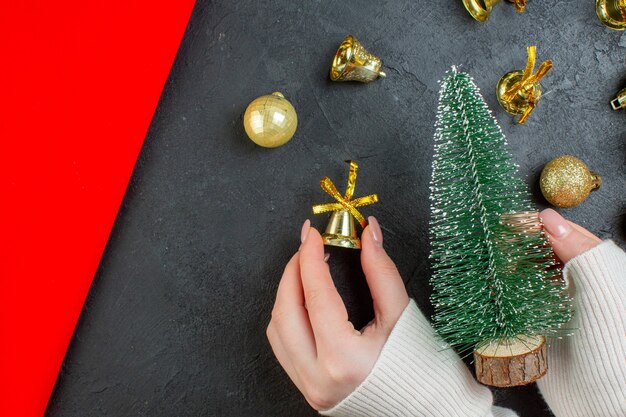 Bovenaanzicht van hand met een kerstboom en decoratie accessoires op donkere tafel
