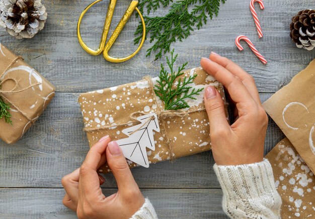 Bovenaanzicht van handen met verpakt kerstcadeau met zuurstokken