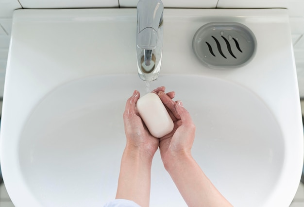 Bovenaanzicht van handen wassen bij de gootsteen met stuk zeep