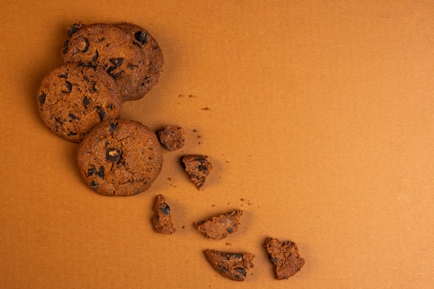Gratis foto bovenaanzicht van havermout koekjes met chocoladeschilfers vallen gebroken met kopie ruimte op oker