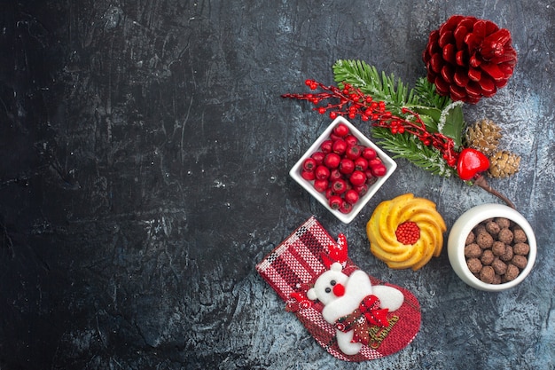 Bovenaanzicht van heerlijke biscuit decoratie accessoire kerstman sok en cornell in een kom dennentakken op donkere ondergrond