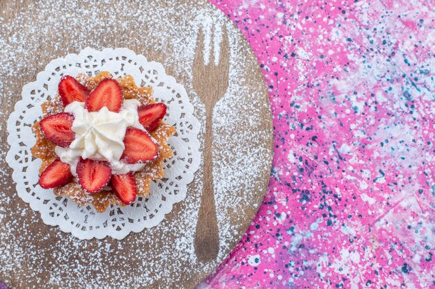 Bovenaanzicht van heerlijke cake met room en gesneden rode aardbeien op helder paars, cake biscuit zoete bak kleur