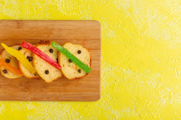 Bovenaanzicht van heerlijke cakeplakken met marmelade op gele ondergrond