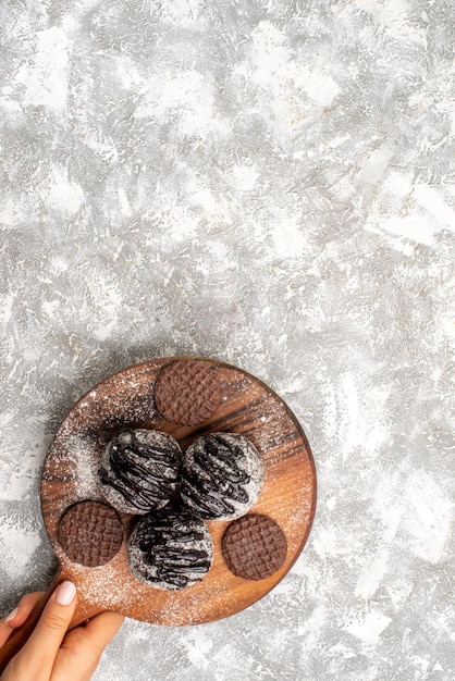 Bovenaanzicht van heerlijke chocolade ballen taarten met koekjes op lichte witte ondergrond