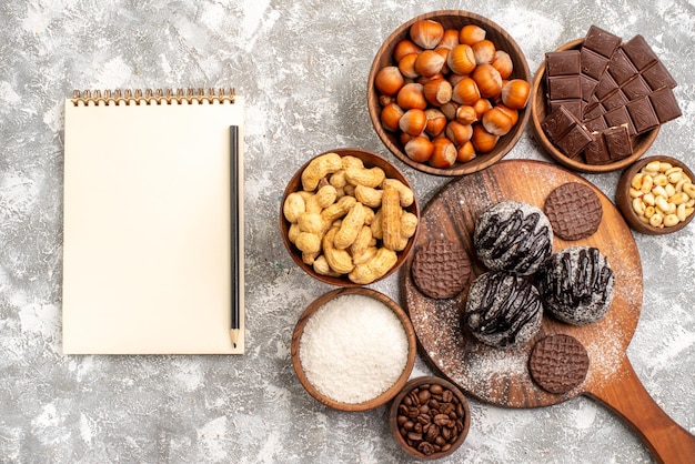 Gratis foto bovenaanzicht van heerlijke chocoladecake met koekjes, noten en pinda's op witte ondergrond