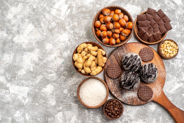 Bovenaanzicht van heerlijke chocoladecake met koekjes, noten en pinda's op witte ondergrond