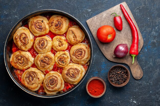 Bovenaanzicht van heerlijke deegmaaltijd met vlees in de pan samen met verse groenten zoals uien tomaten op donkergrijs bureau, voedsel maaltijd vlees groente