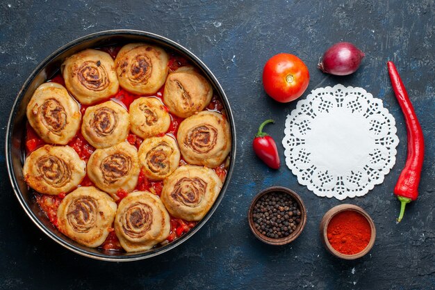 Bovenaanzicht van heerlijke deegmaaltijd met vlees in de pan samen met verse groenten zoals uien, tomaten op donkergrijs bureau, voedselmaaltijd vlees