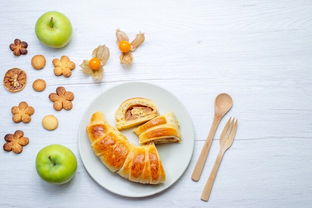 bovenaanzicht van heerlijke gesneden gebakjes in plaat met vulling samen met appels en koekjes op wit, gebak cookie koekje zoete suiker