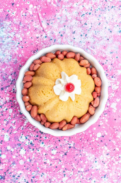 Bovenaanzicht van heerlijke gewone cake met room en verse pinda's op heldere, zoete suikernoot van het cakekoekje