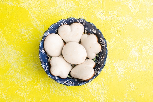 Bovenaanzicht van heerlijke koekjes in plaat op de gele vloer