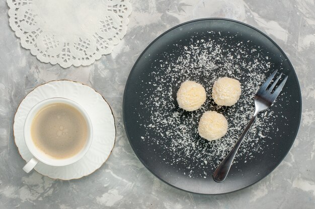 Bovenaanzicht van heerlijke kokos snoepjes met koffie op witte ondergrond