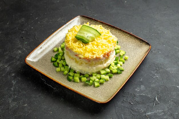 Bovenaanzicht van heerlijke salade geserveerd met gehakte komkommer op donkere achtergrond