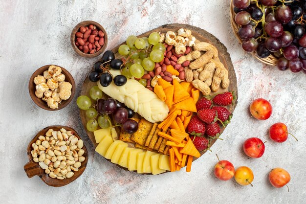 Bovenaanzicht van heerlijke snacks cips druiven kaas en noten op witte ondergrond