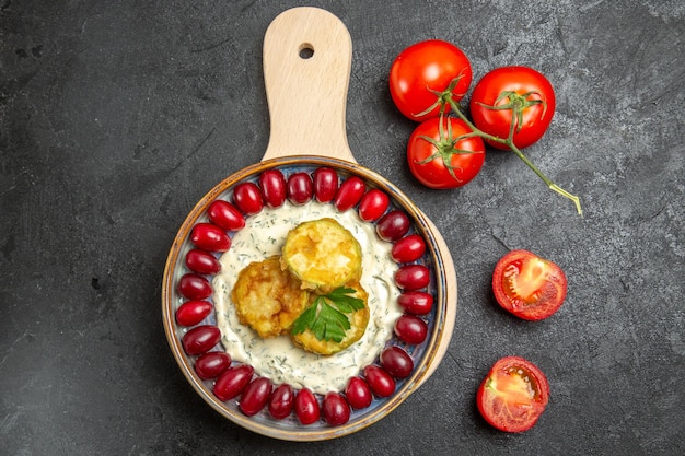 Bovenaanzicht van heerlijke squashmaaltijd met verse rode kornoeljes en tomaten op grijze ondergrond