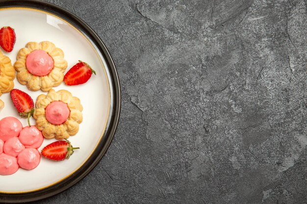 Bovenaanzicht van heerlijke suikerkoekjes met aardbeigelei op grijze ondergrond