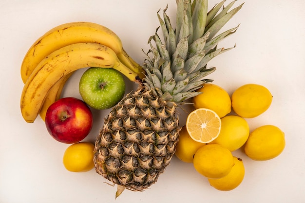 Gratis foto bovenaanzicht van heerlijke vruchten zoals bananen ananas kleurrijke appel en citroenen geïsoleerd op een witte muur