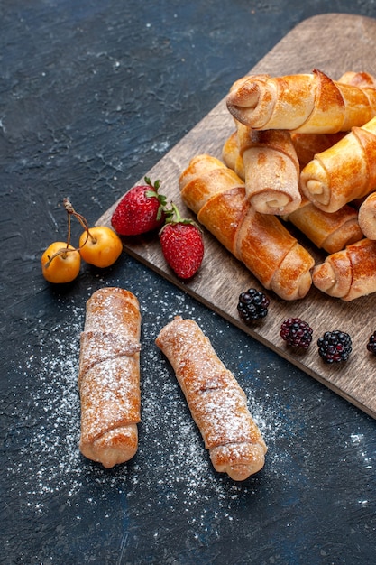 Gratis foto bovenaanzicht van heerlijke zoete armbanden met lekkere vulling gebakken met fruit op donkere vloer bak cake biscuit suiker zoet dessert