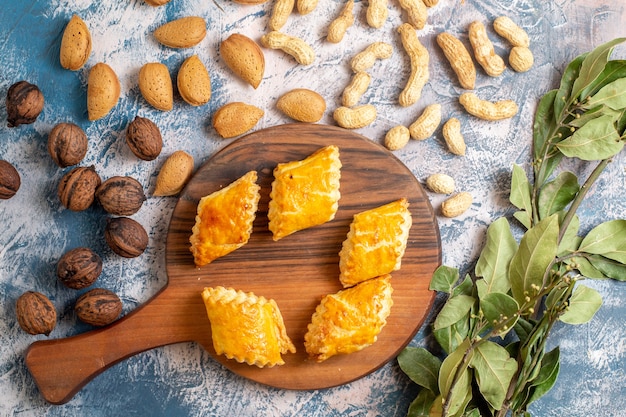 Bovenaanzicht van heerlijke zoete gebakjes met noten op blauwe ondergrond