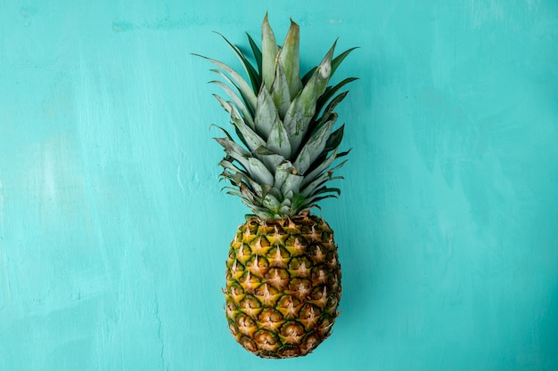 Bovenaanzicht van hele ananas op blauw oppervlak