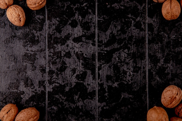 Bovenaanzicht van hele walnoten op zwarte houten achtergrond met kopie ruimte