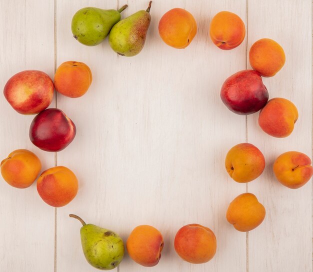 Bovenaanzicht van het patroon van fruit als perzik abrikoos en peer in ronde vorm op houten achtergrond met kopie ruimte