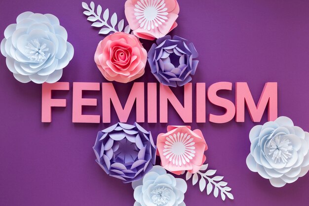 Bovenaanzicht van het woord feminisme met papieren bloemen voor Vrouwendag