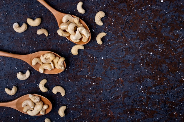 Bovenaanzicht van houten lepels met gezouten geroosterde pistachenoten op zwarte achtergrond met kopie ruimte