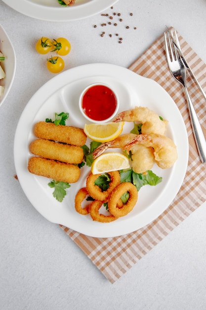 Bovenaanzicht van inktvis en garnalen tempura en gebakken kaas stick op een witte plaat