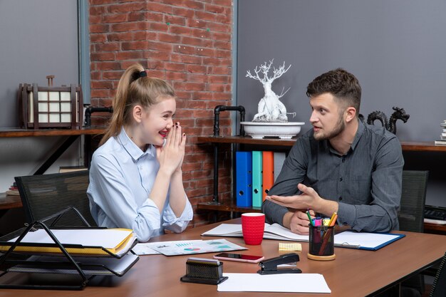 Bovenaanzicht van jonge hardwerkende managementmedewerkers die één probleem bespreken met een verbaasde gezichtsuitdrukking in een kantooromgeving