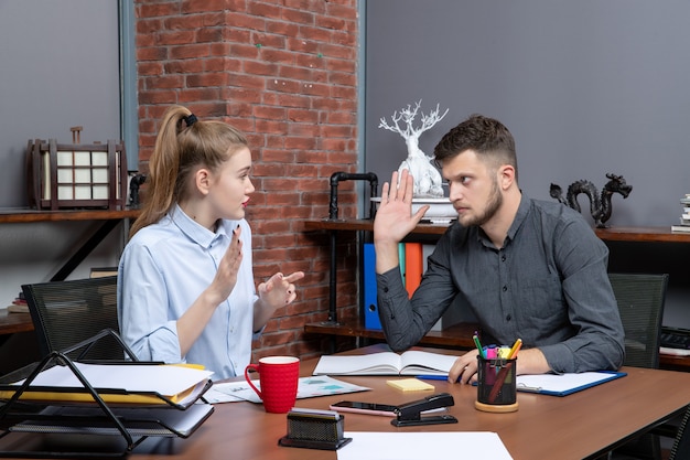 Bovenaanzicht van jonge man en vrouwelijke collega die één probleem bespreken in een kantooromgeving