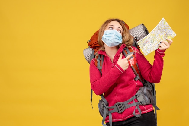 Gratis foto bovenaanzicht van jonge reizende meisje in medische masker haar bagage verzamelen en kaart tonen