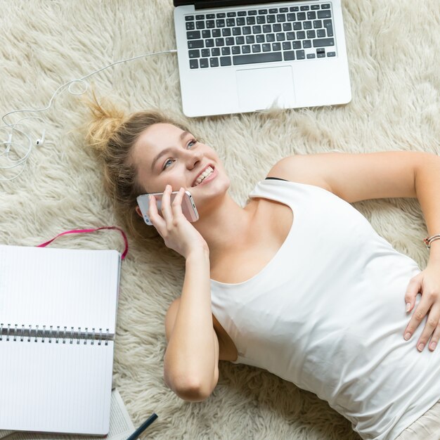 Bovenaanzicht van jonge vrouw die op telefoon thuis klopt