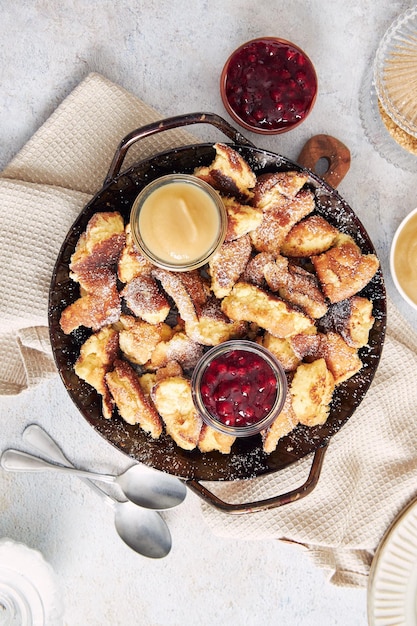 Bovenaanzicht van kaiserschmarrn met gescheurde pannenkoeken, veenbessenjam en appelpuree op een tafel