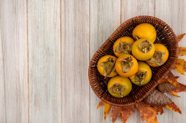 Bovenaanzicht van kaki fruit op een emmer op een grijze houten tafel met kopie ruimte