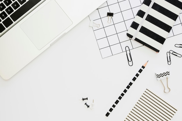 Bovenaanzicht van kantoorbenodigdheden met laptop en paperclips