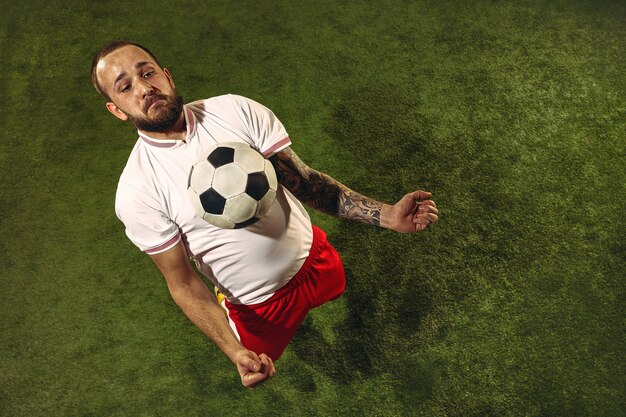 Bovenaanzicht van Kaukasische voetbal of voetballer op groene muur van gras.