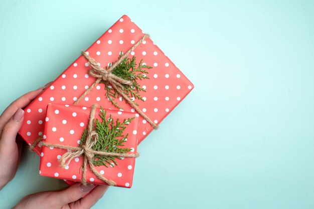 Bovenaanzicht van Kerstmis achtergrond met hand met rode geschenkdozen op pastel groene achtergrond