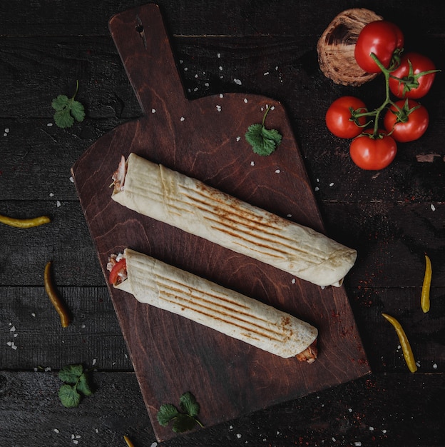 Bovenaanzicht van kip doner verpakt in lavash op een houten snijplank