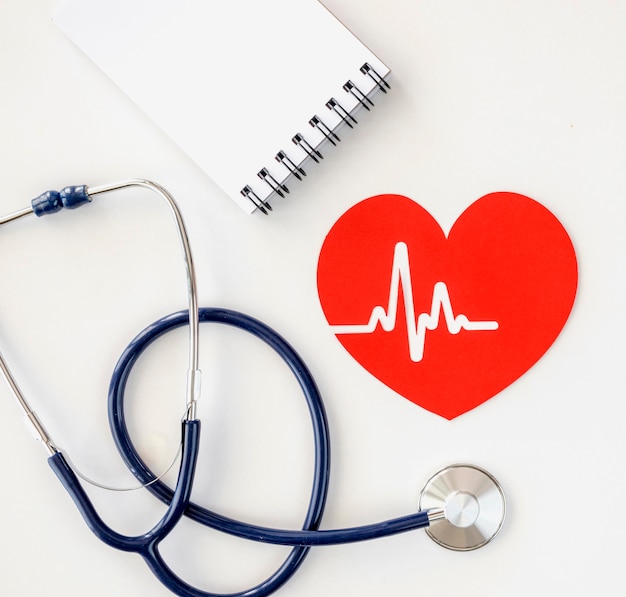 Gratis foto bovenaanzicht van kladblok met stethoscoop en papier hart