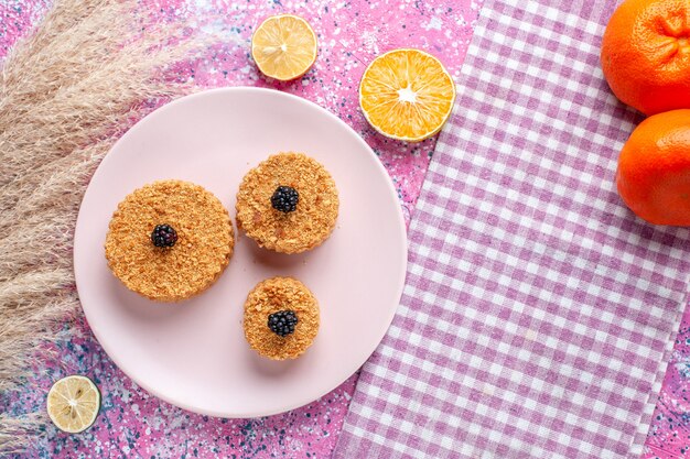 Bovenaanzicht van kleine cakes met bessen op roze oppervlak