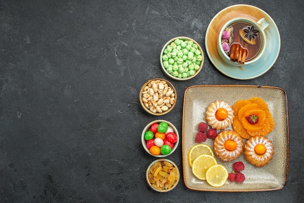 Bovenaanzicht van kleine lekkere taarten met snoep, fruit en noten op grijs