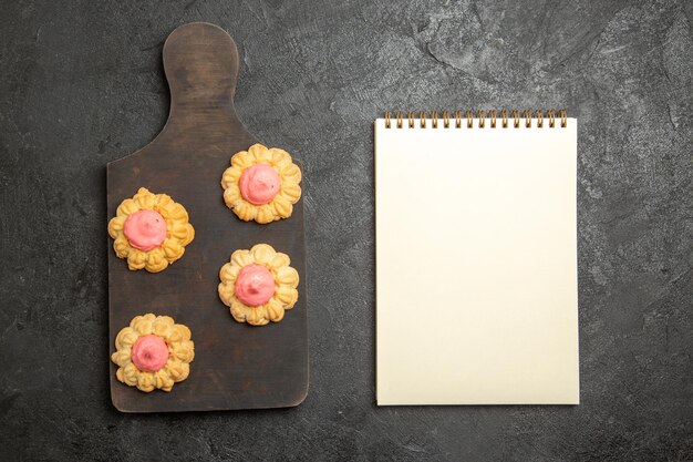 Bovenaanzicht van kleine suikerkoekjes met aardbeienroom op het grijze oppervlak