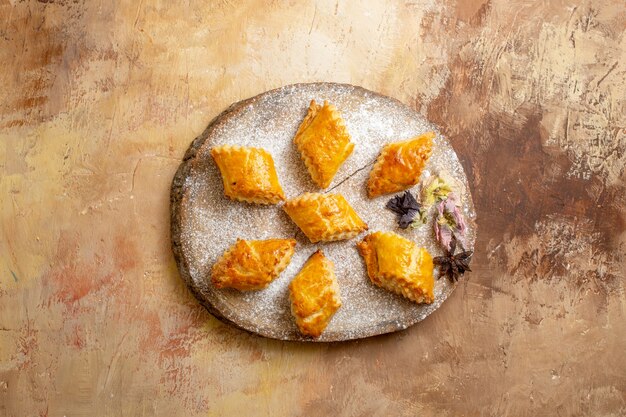 Bovenaanzicht van kleine zoete gebakjes voor thee op lichte vloer